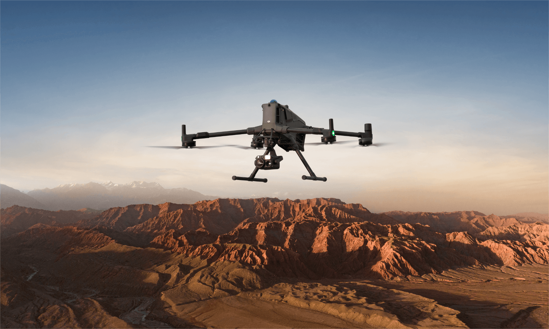 DJI Matrice 400 drone carrying a camera over a mountainous field landscape