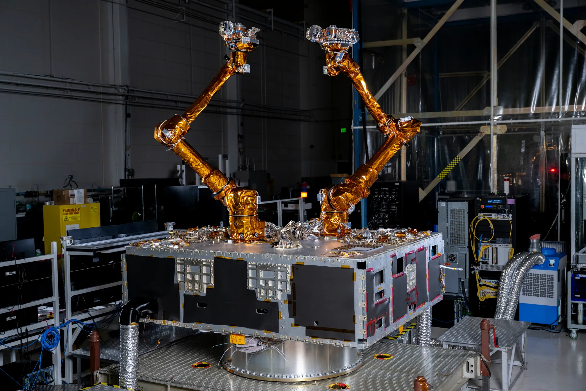 Two robotic servicing arms wrapped in gold material mounted on a black and silver spacecraft assembly.